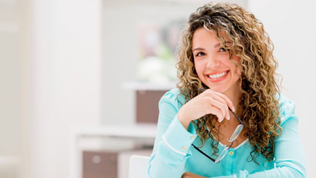 A woman with curly hair sits at a table, looking happy and content with the meaningful life that she has created.